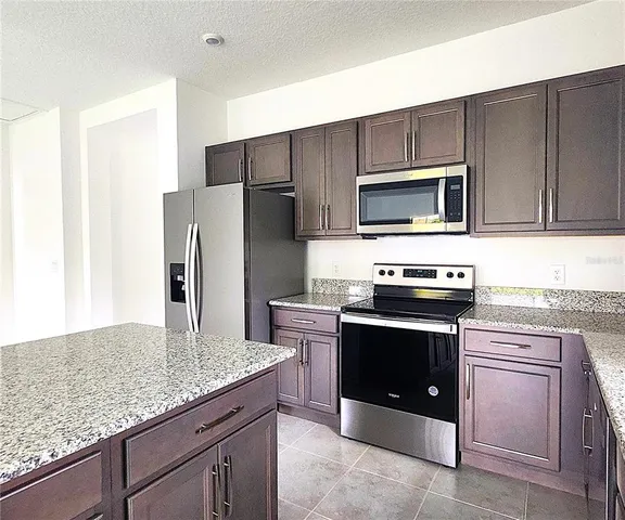 a kitchen with granite countertop wooden cabinets and stainless steel appliances