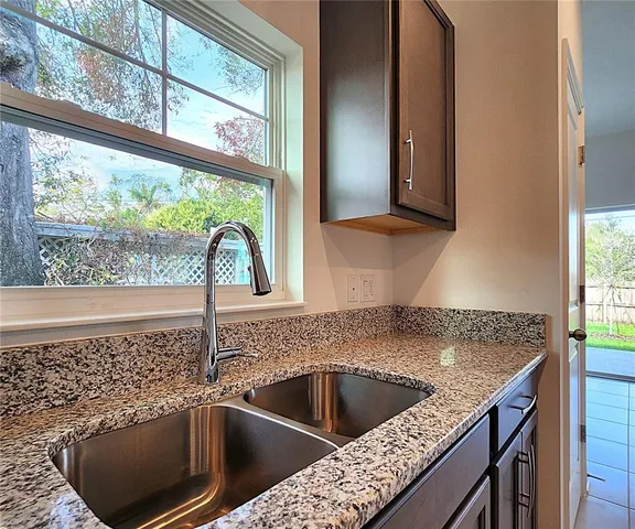 a kitchen with a sink and a large mirror next to a window