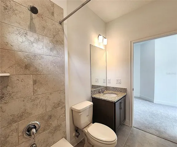 a bathroom with a granite countertop toilet sink and mirror