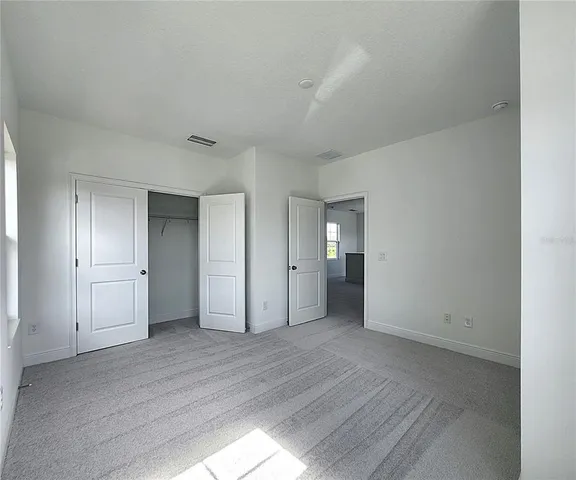 an empty room with closet area and wooden floor