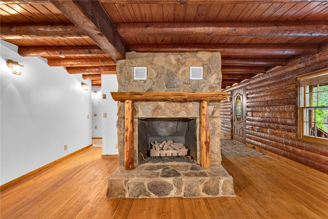 237 Spring Valley Road Liberty, SC 29657 - Photo 6 of 50 A grand stone fireplace grounds this rustic space with natural wood beams and plank flooring.