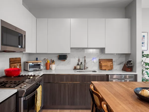 a kitchen with stainless steel appliances a stove a sink a microwave cabinets and a dining table