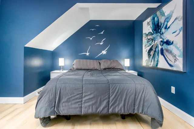 a bedroom with a bed and painting on the wall