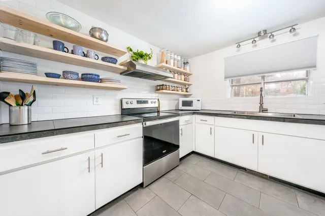 a white kitchen with stainless steel appliances granite countertop white cabinets a sink and dishwasher