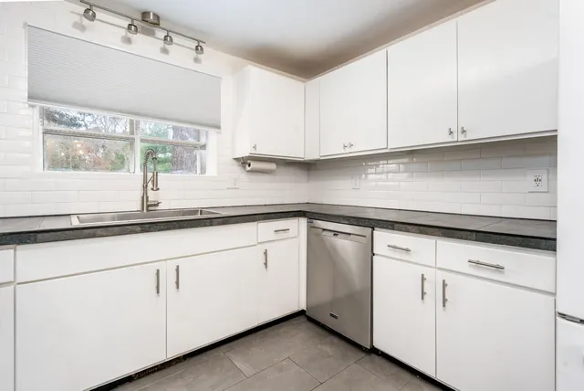 a kitchen with granite countertop white cabinets and white appliances