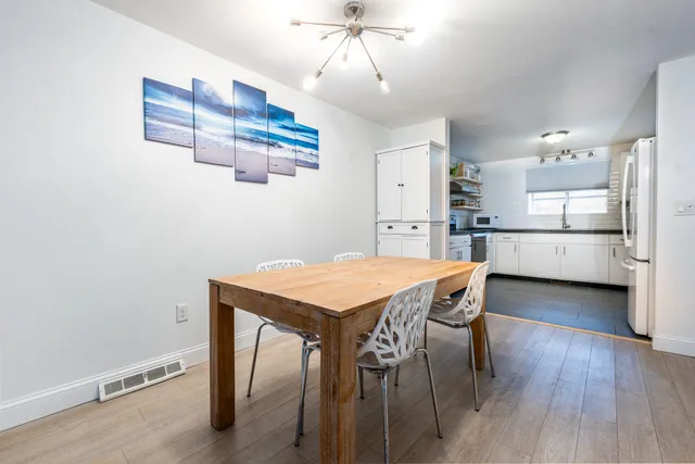 a kitchen with stainless steel appliances a dining table chairs and wooden floor