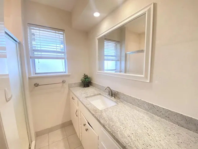 a bathroom with a granite countertop sink and a window