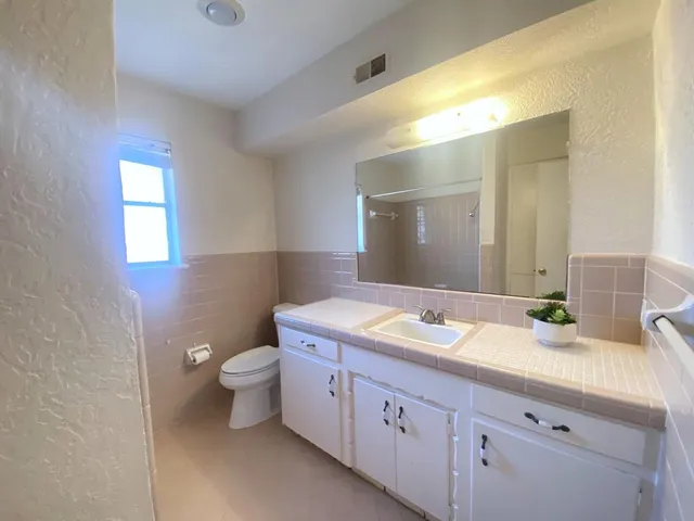 a bathroom with a granite countertop toilet sink and mirror