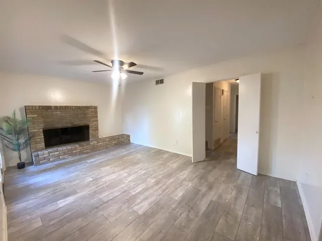 a view of empty room with wooden floor and fireplace