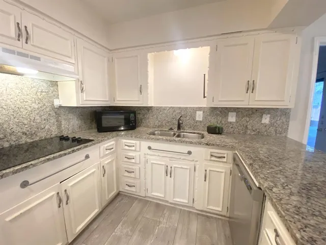 a kitchen with granite countertop white cabinets and white appliances