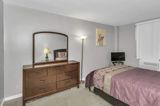 a bedroom with a bed and a mirror on dresser