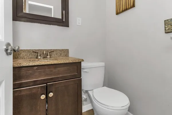 a bathroom with a granite countertop toilet and a sink