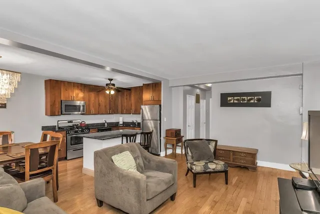a living room with furniture kitchen view and a wooden floor