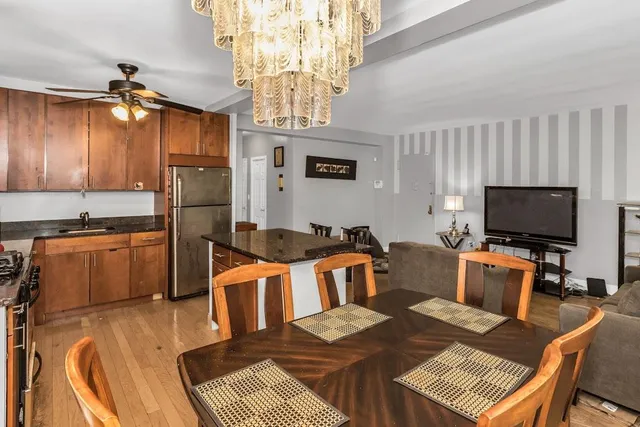 a kitchen with stainless steel appliances granite countertop a stove a refrigerator a kitchen island a sink dishwasher a stove and a dining table with wooden floor