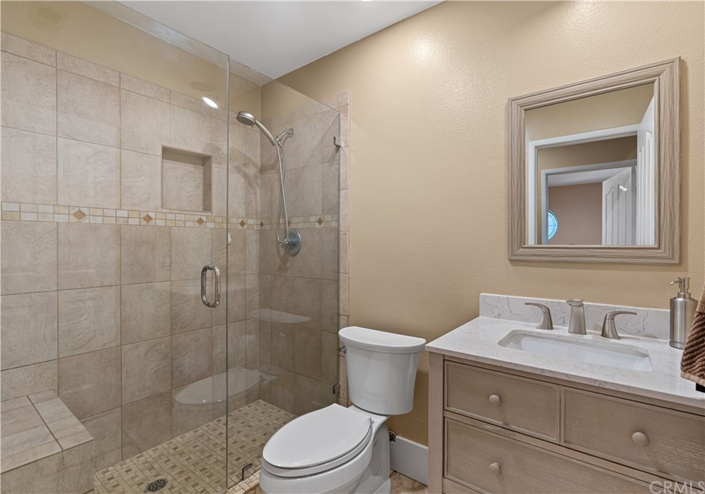 1879 Apostle Lane Riverside, CA 92506 - Photo 30 of 49 a bathroom with a granite countertop toilet a sink a mirror and shower