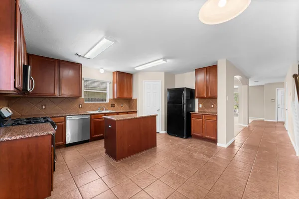 a kitchen with stainless steel appliances granite countertop a refrigerator and a stove top oven