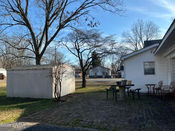 a view of a backyard with table and chairs and a large tree