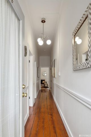 a view of a hallway with wooden floor and a chandelier