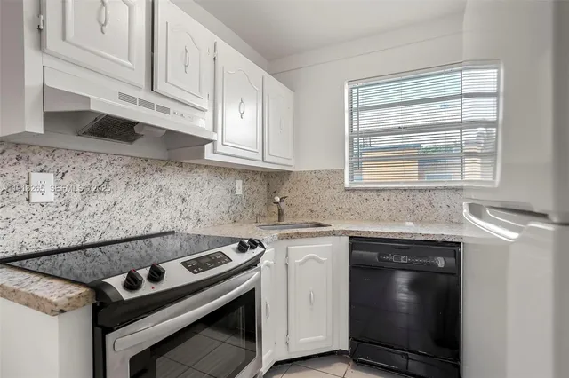 a kitchen with granite countertop a stove sink and cabinets