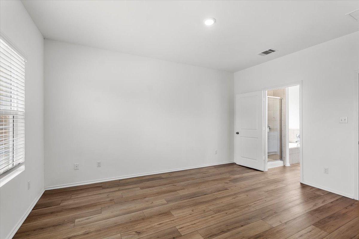 448 Perfect World Loop Jarrell, TX 76537 - Photo 25 of 40 A spacious primary bedroom features rich wood flooring and direct bathroom access.