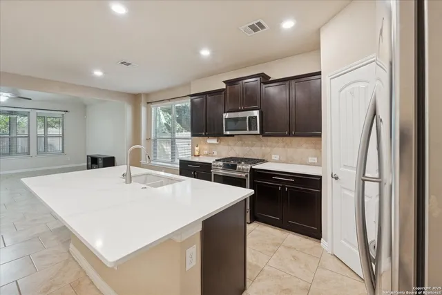 a kitchen with kitchen island a counter top space cabinets and stainless steel appliances