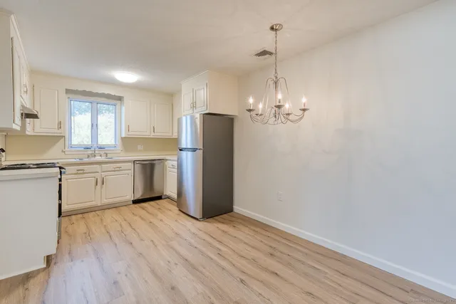 a kitchen with a refrigerator a sink dishwasher a stove and white cabinets with wooden floor