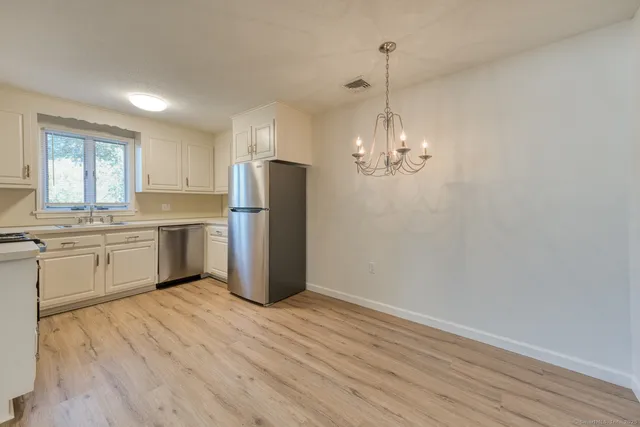 a kitchen with stainless steel appliances granite countertop a refrigerator a sink dishwasher a stove and white countertops with wooden floor