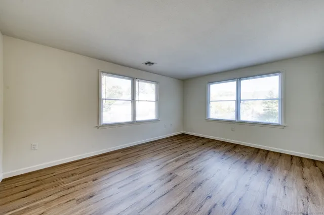 an empty room with wooden floor and windows