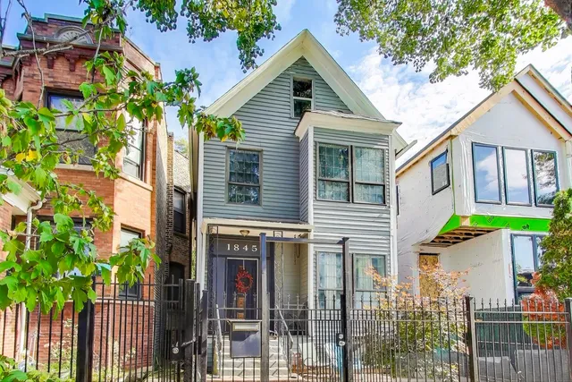 a view of a brick house with large windows and a small yard