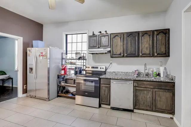 a kitchen with stainless steel appliances granite countertop a refrigerator and a stove top oven