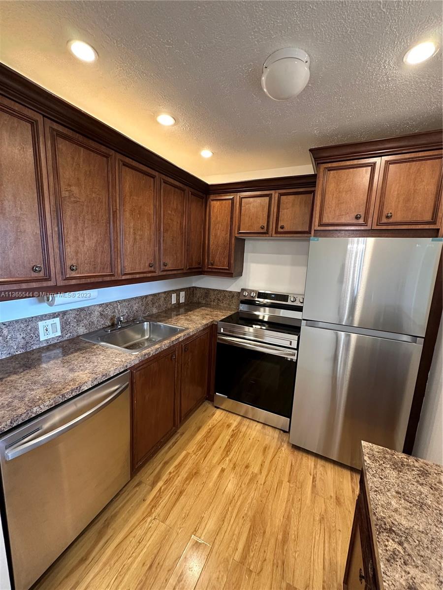 538 Mansfield M, Unit 538 Boca Raton, FL 33434 - Photo 2 of 13 a kitchen with granite countertop stainless steel appliances and wooden cabinets