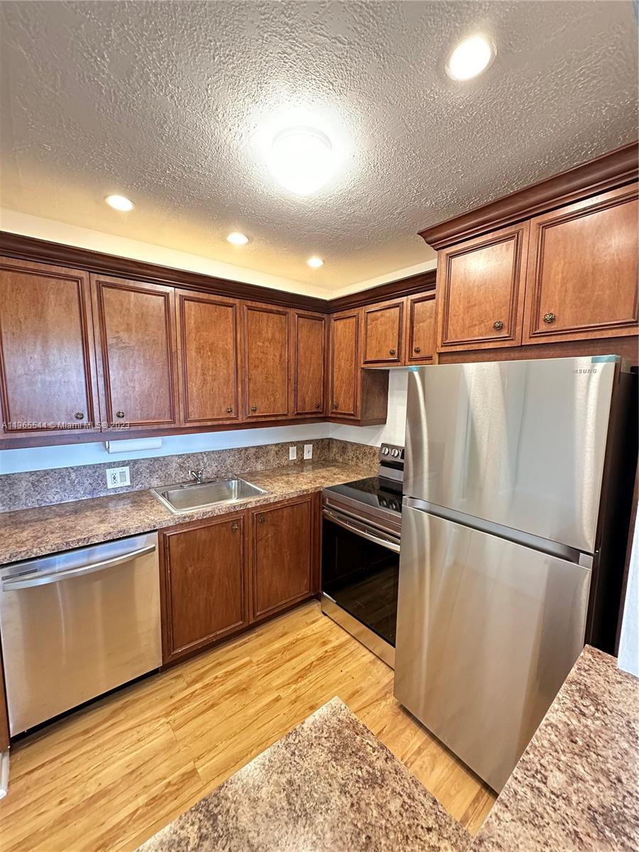 538 Mansfield M, Unit 538 Boca Raton, FL 33434 - Photo 3 of 13 a kitchen with granite countertop a refrigerator and a stove top oven