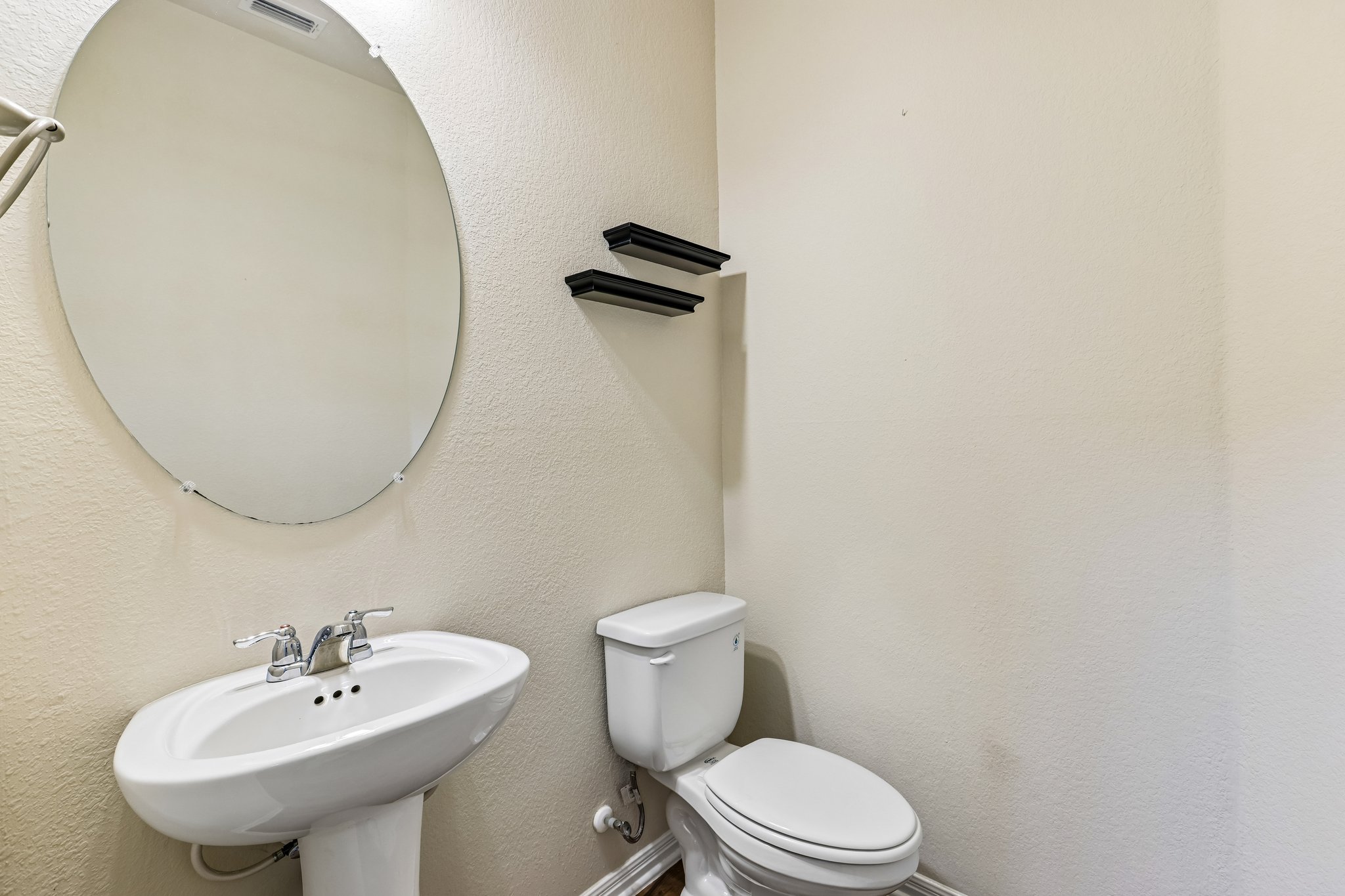 808 Totis Road Austin, TX 78748 - Photo 32 of 40 Pedestal sink with chrome faucet, oval frameless mirror, and neutral wall tones