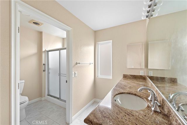 a en suite bathroom with a granite countertop sink and a granite countertop tub