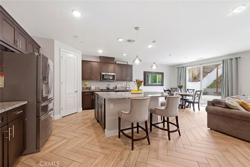 20948 Center Street Riverside, CA 92507 - Photo 28 of 92 a kitchen with stainless steel appliances kitchen island granite countertop a refrigerator a stove a sink a dining table and chairs with wooden floor