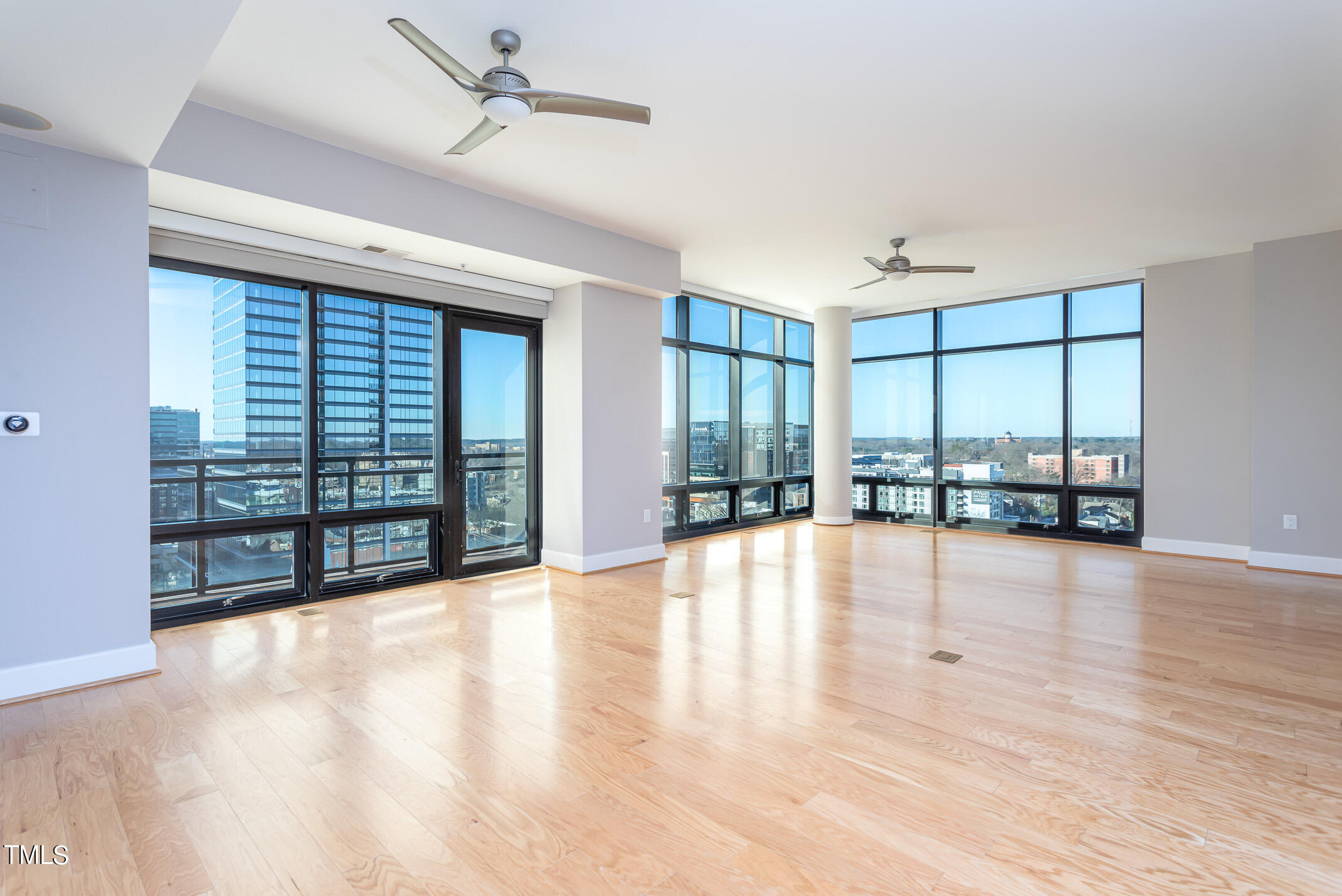 a view of an empty room with a floor to ceiling window and wooden floor