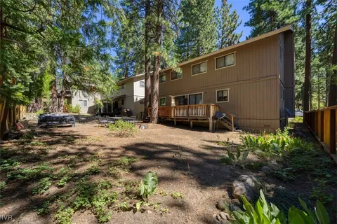 a backyard of a house with large trees and outdoor seating