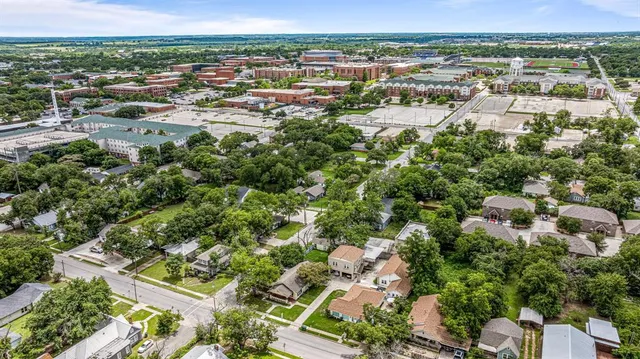 an aerial view of residential houses with outdoor space and trees