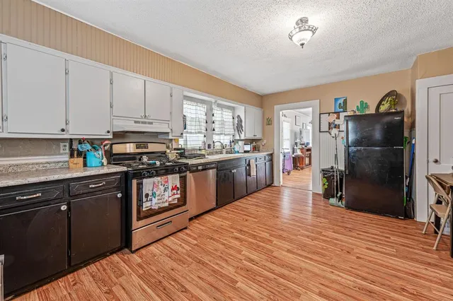 a kitchen with stainless steel appliances granite countertop a refrigerator a stove top oven a sink and dishwasher with wooden floor