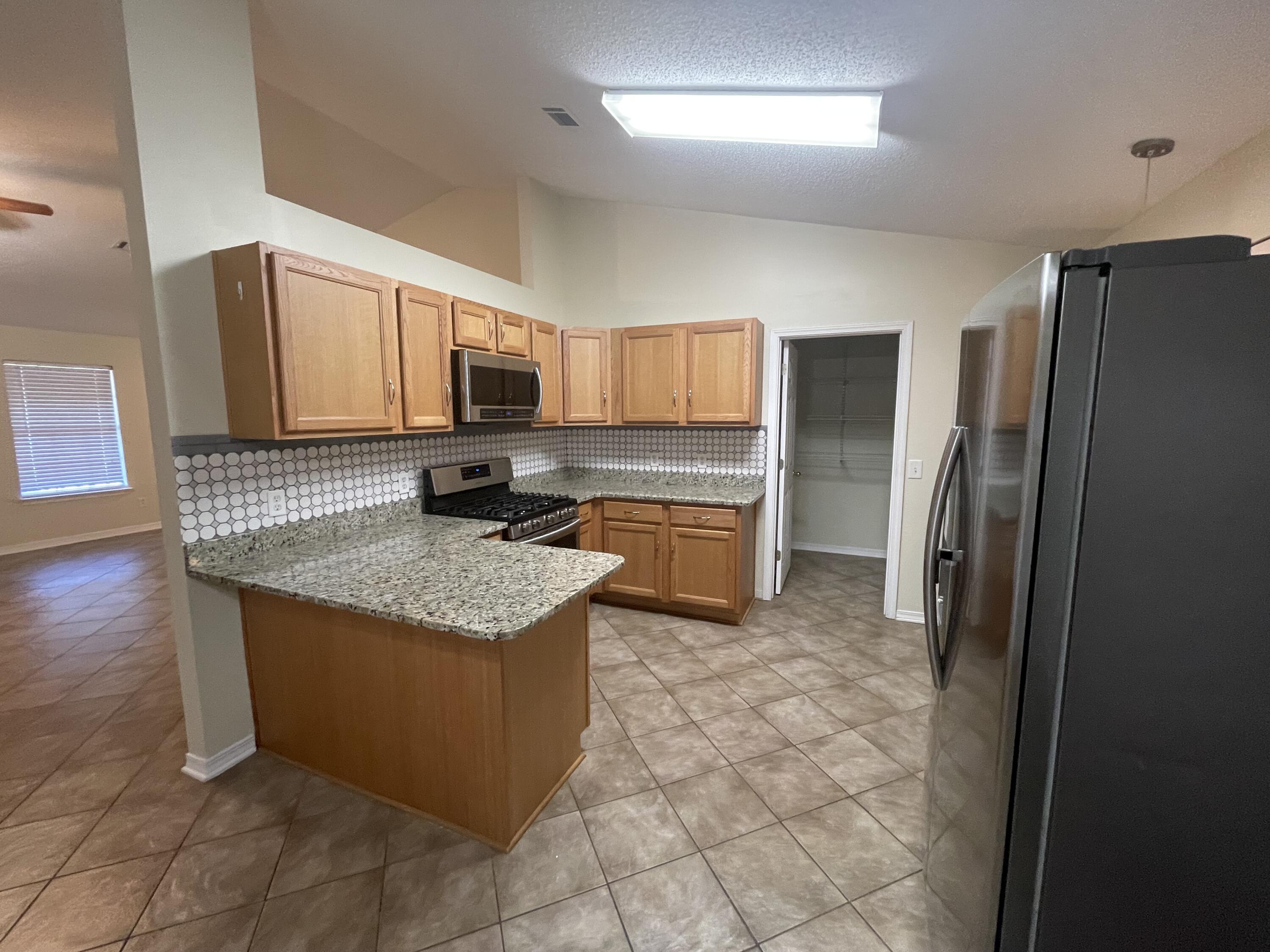 105 Steeplechase Drive Crestview, FL 32539 - Photo 2 of 14 a kitchen with stainless steel appliances granite countertop a stove a refrigerator a sink a microwave and island
