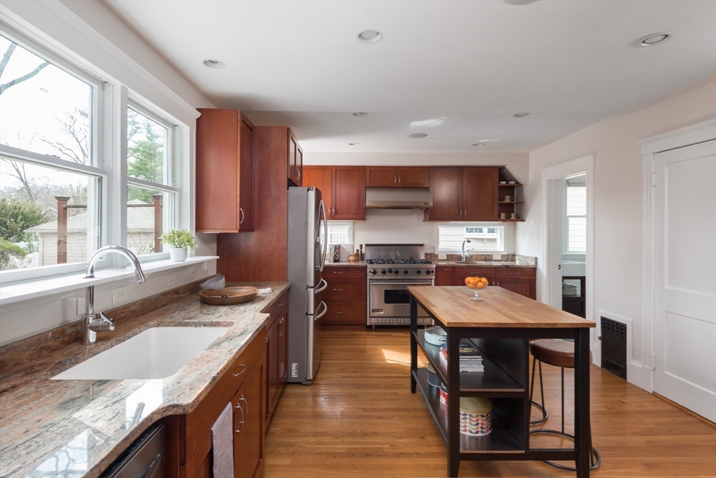 33 Ottawa Road Arlington, MA 02476 - Photo 12 of 38 a kitchen with stainless steel appliances granite countertop a table chairs sink refrigerator and cabinets