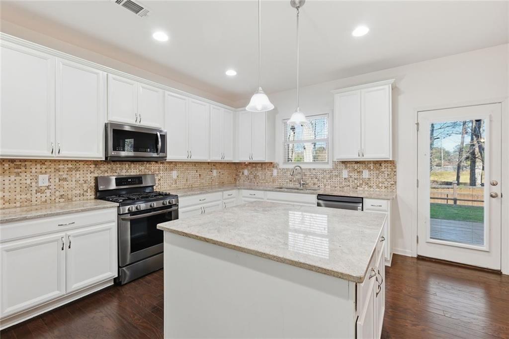 2495 Matlin Way Buford, GA 30519 - Photo 14 of 36 a kitchen with granite countertop white cabinets and black stainless steel appliances