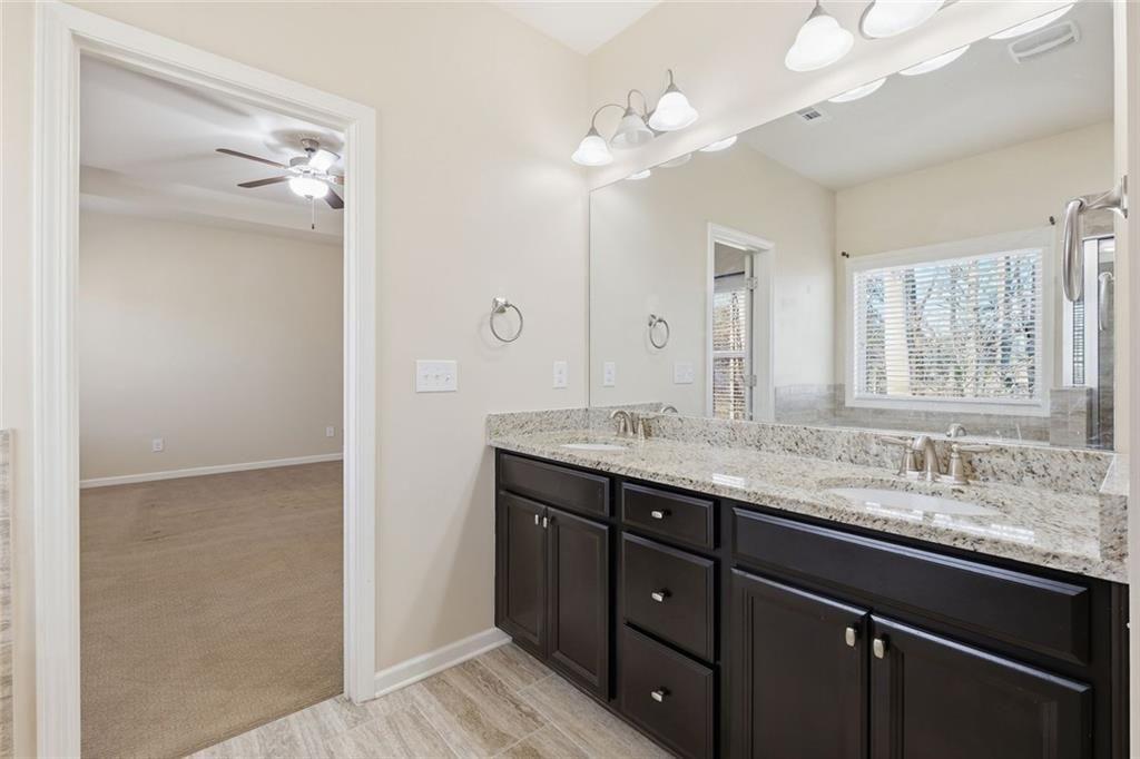 2495 Matlin Way Buford, GA 30519 - Photo 22 of 36 a bathroom with a granite countertop sink a large mirror and a shower