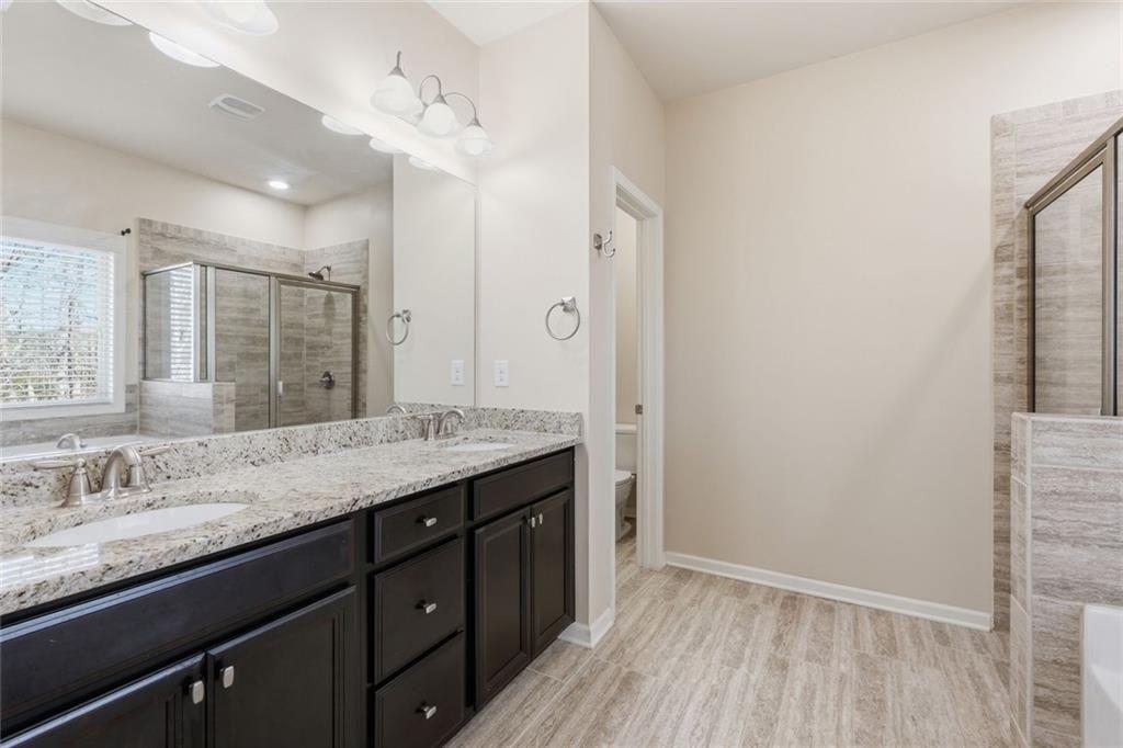2495 Matlin Way Buford, GA 30519 - Photo 23 of 36 a bathroom with a granite countertop sink a mirror and a shower