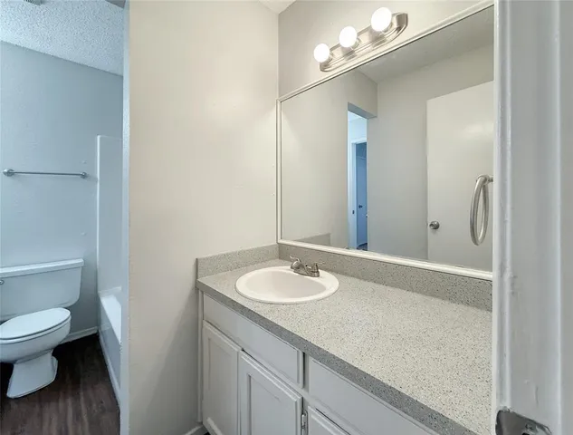 a bathroom with a granite countertop sink a toilet and a mirror
