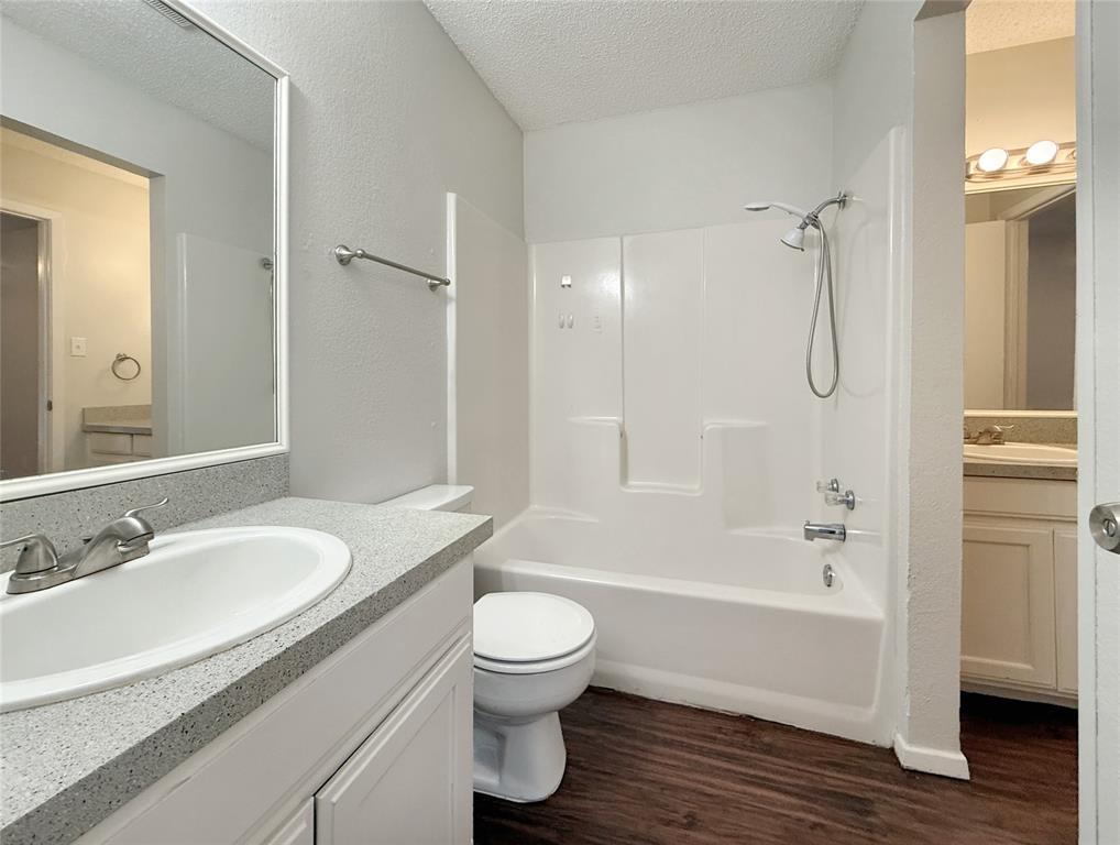 425 Southwest Thomas Street, Unit B Burleson, TX 76028 - Photo 18 of 22 a bathroom with a granite countertop toilet a sink and a bathtub