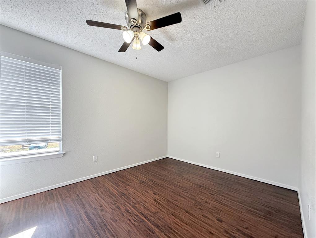 425 Southwest Thomas Street, Unit B Burleson, TX 76028 - Photo 19 of 22 an empty room with wooden floor ceiling fan and windows