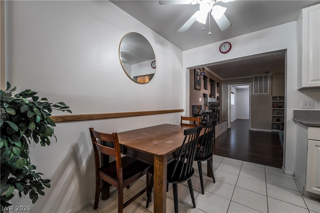 1324 Appaloosa Road Boulder City, NV 89005 - Photo 6 of 42 A well-lit dining area featuring a smooth wooden table and tile flooring flows into a darker-toned living space.