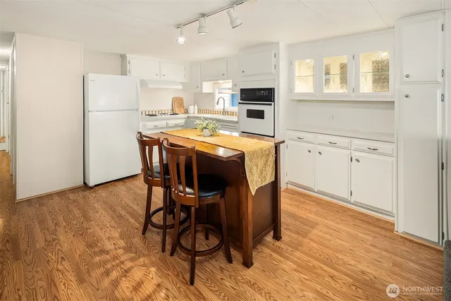 a kitchen with stainless steel appliances a stove a sink refrigerator and white cabinets with wooden floor