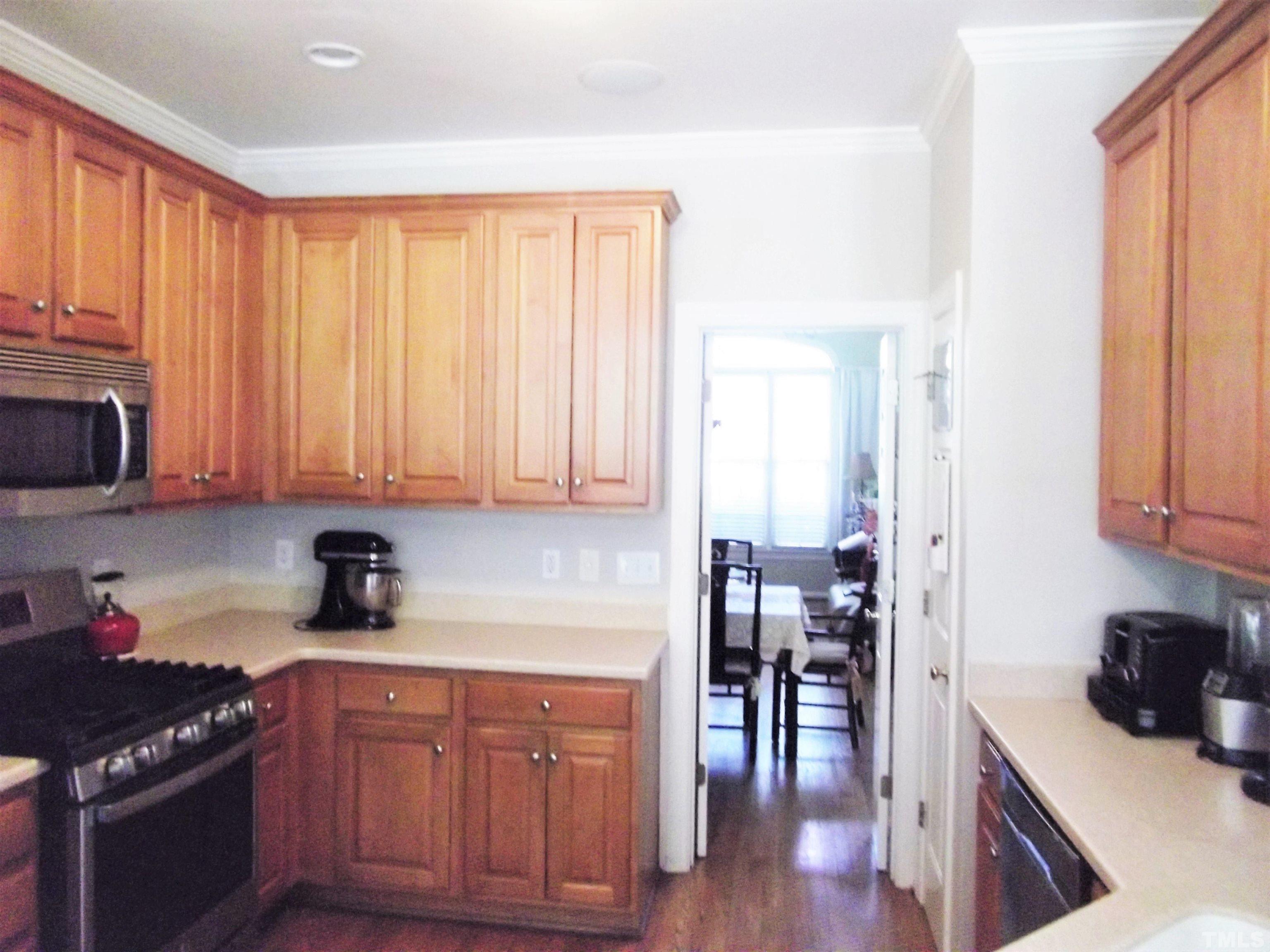 7912 Milltrace Run Raleigh, NC 27615 - Photo 13 of 36 a kitchen with stainless steel appliances granite countertop wooden cabinets a stove top oven a sink and dishwasher with wooden floor